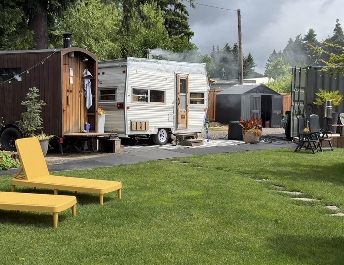 The two saunas in the yard, smoke rising off the stove, loungers on the grass